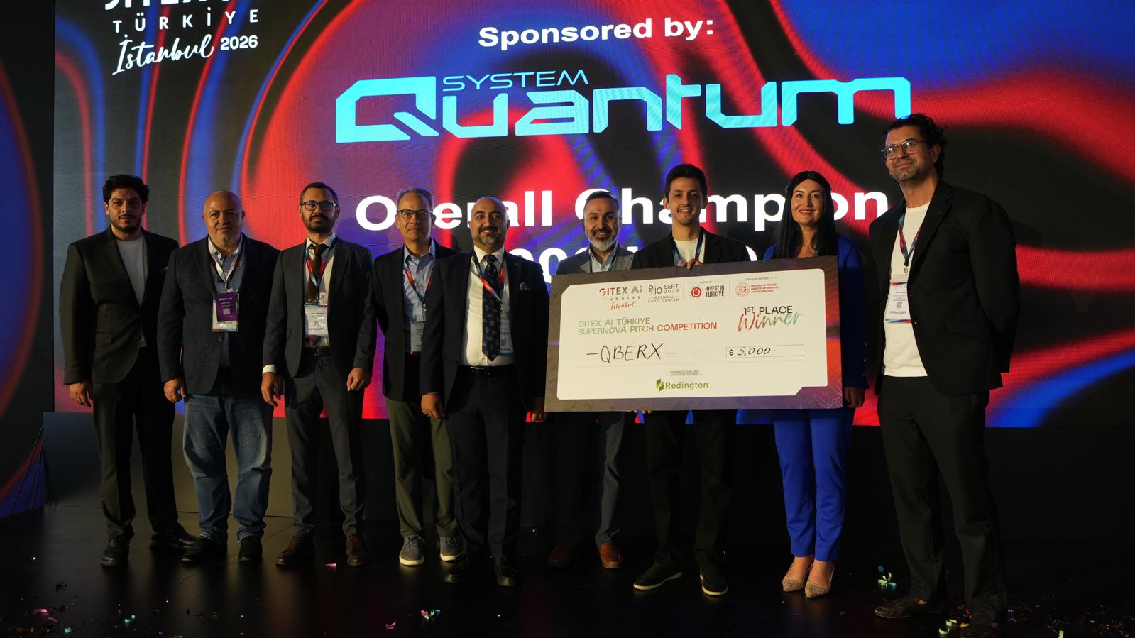 GITEX AI Türkiye 2026 Supernova Pitch Competition ödül töreni: QBERX ekibi, üzerinde QBERX, 5.000 dolar ve 1st Place Winner yazan dev çeki sahnede tutuyor