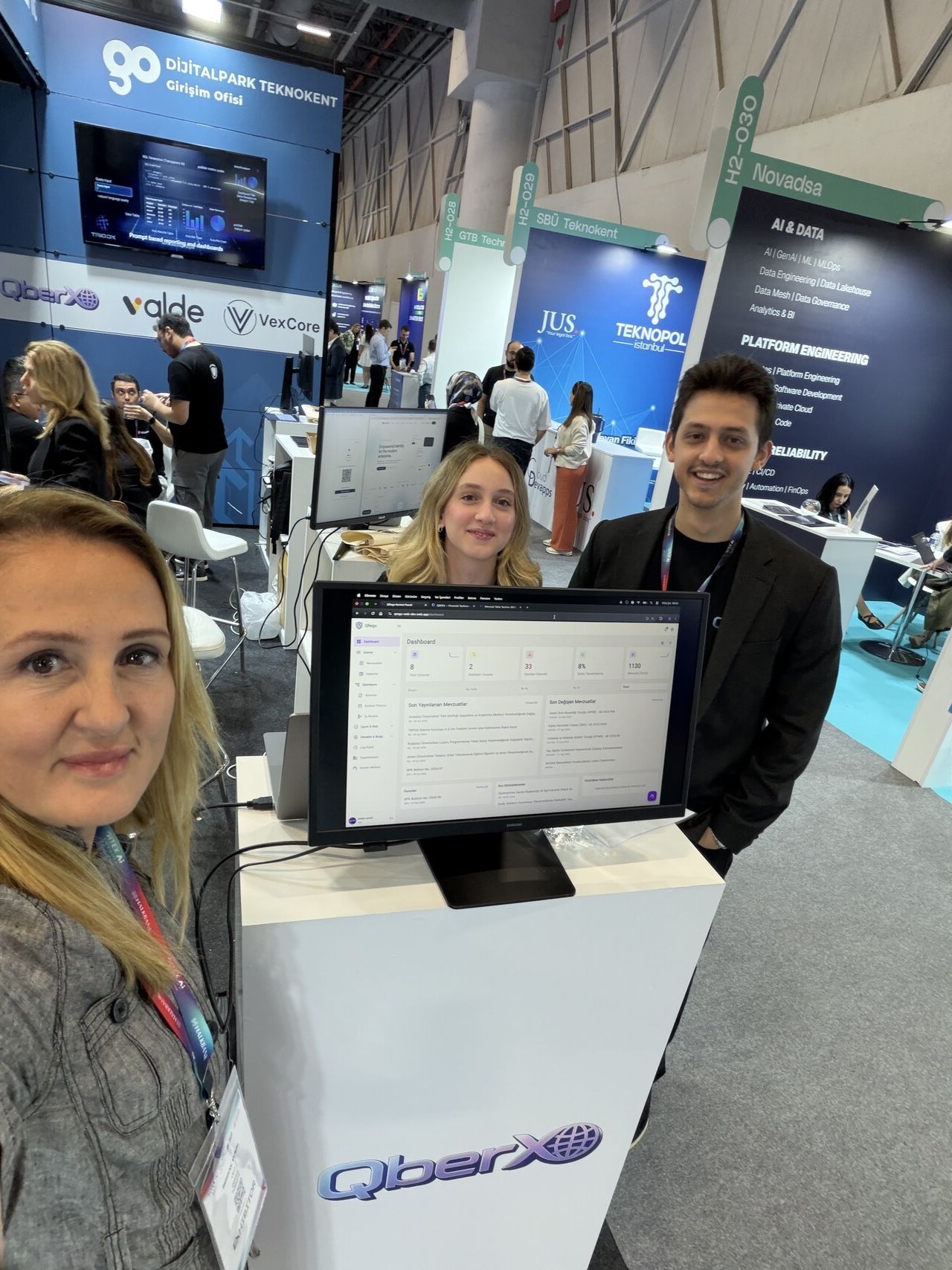 QBERX ekibi GITEX AI Türkiye 2026 standında; önlerindeki ekranda QRegu uyum panosu açık, arkada Dijitalpark Teknokent Girişim Ofisi alanı